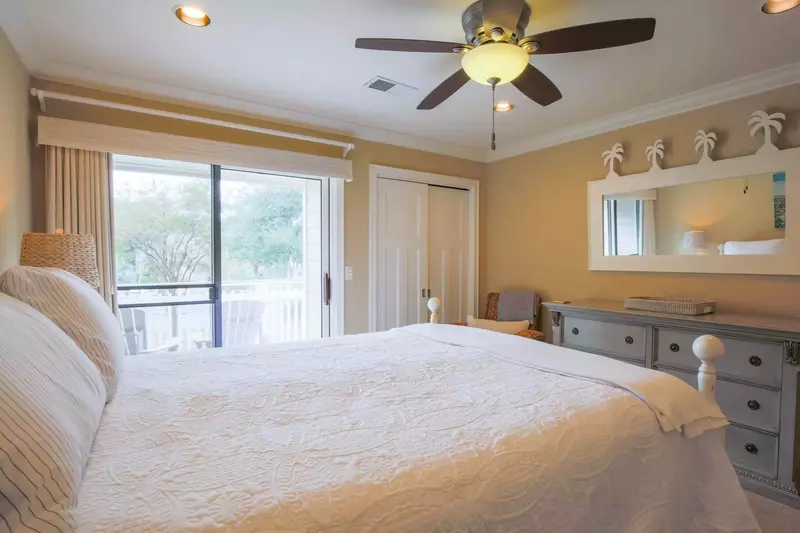 This guest bedroom, which overlooks the street in front of the house, has a dresser and ceiling fan.