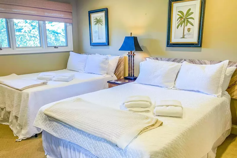 This guest suite features a queen bed, a full bed and a night stand with a reading lamp.