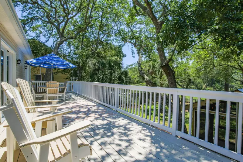 The back deck features Adirondack chairs, a dining table that seats 6 and views of the trees lining the backyard.