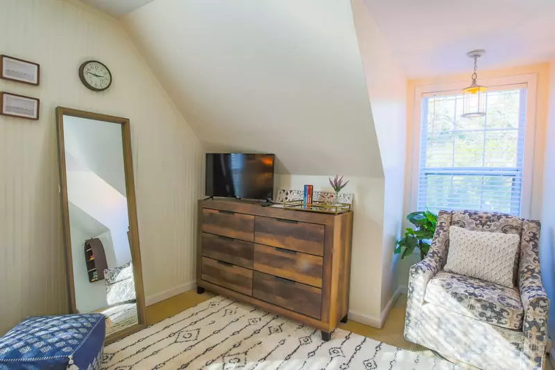 This guest bedroom also features a dresser, a smart TV and an arm chair.