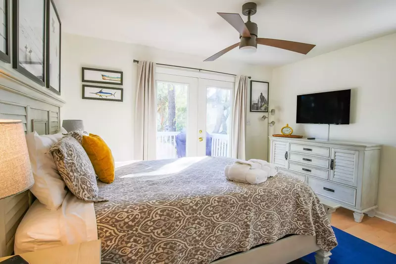This lower level bedroom features a queen bed, dresser and wall-mounted smart TV.