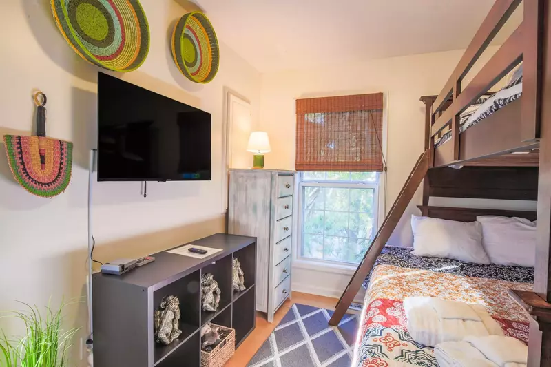 The bunk bedroom features a wall-mounted smart TV and a dresser.