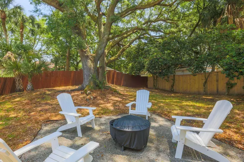 There is a fire pit with Adirondack chairs in the backyard.