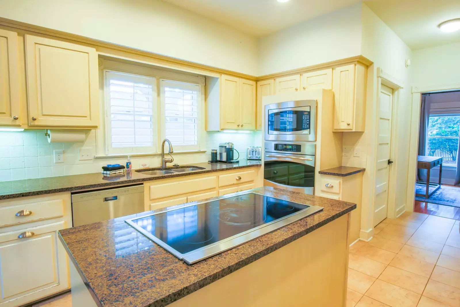 The kitchen features stainless steel appliances, central island, a tiled backsplash and off-white cabinets.