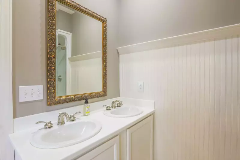 The downstairs en suite bathroom has a two sink vanity and beadboard paneling.