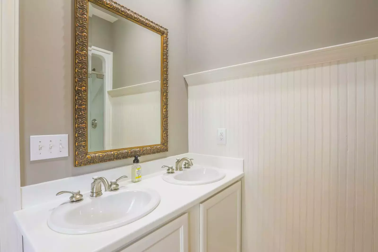 The downstairs en suite bathroom has a two sink vanity and beadboard paneling.