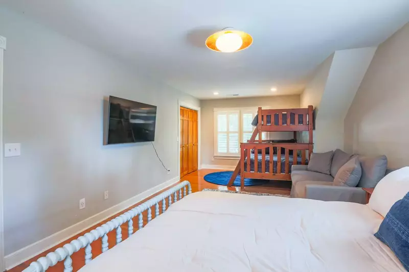 The bunk bedroom features a wall-mounted smart TV and sofa.