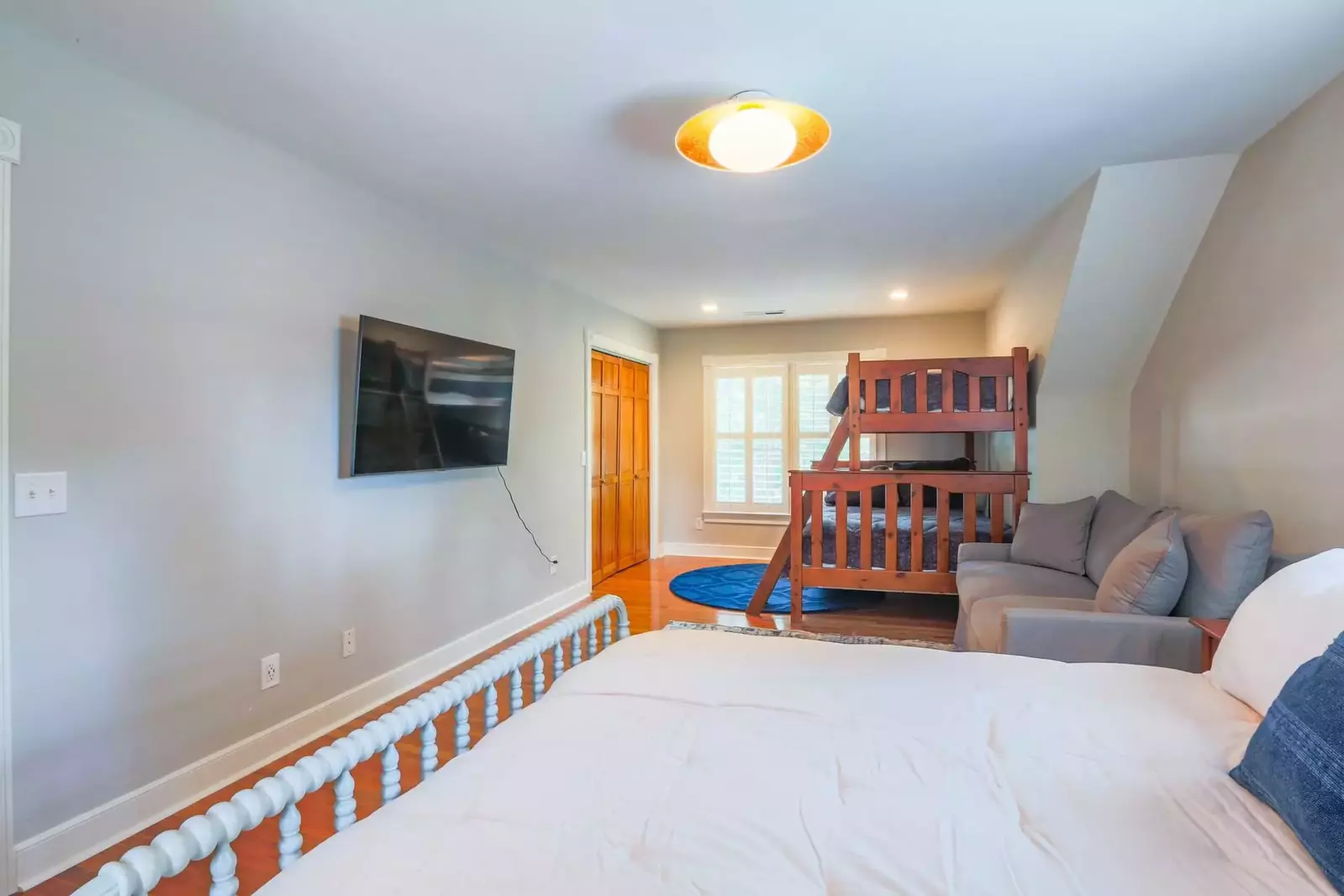 The bunk bedroom features a wall-mounted smart TV and sofa.