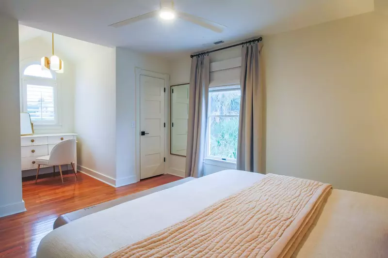 This guest bedroom also features a ceiling fan, dresser and full length mirror.