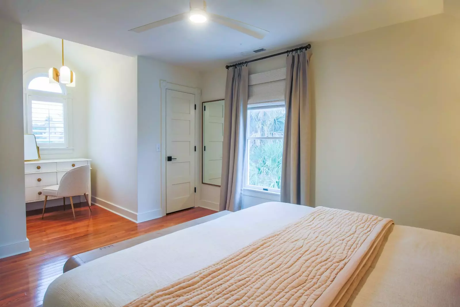 This guest bedroom also features a ceiling fan, dresser and full length mirror.