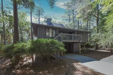 Riverhouse is an elevated home with a driveway and carport area beneath the home.