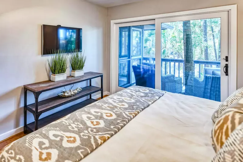 The master bedroom also has a wall-mounted smart TV and a ceiling fan.