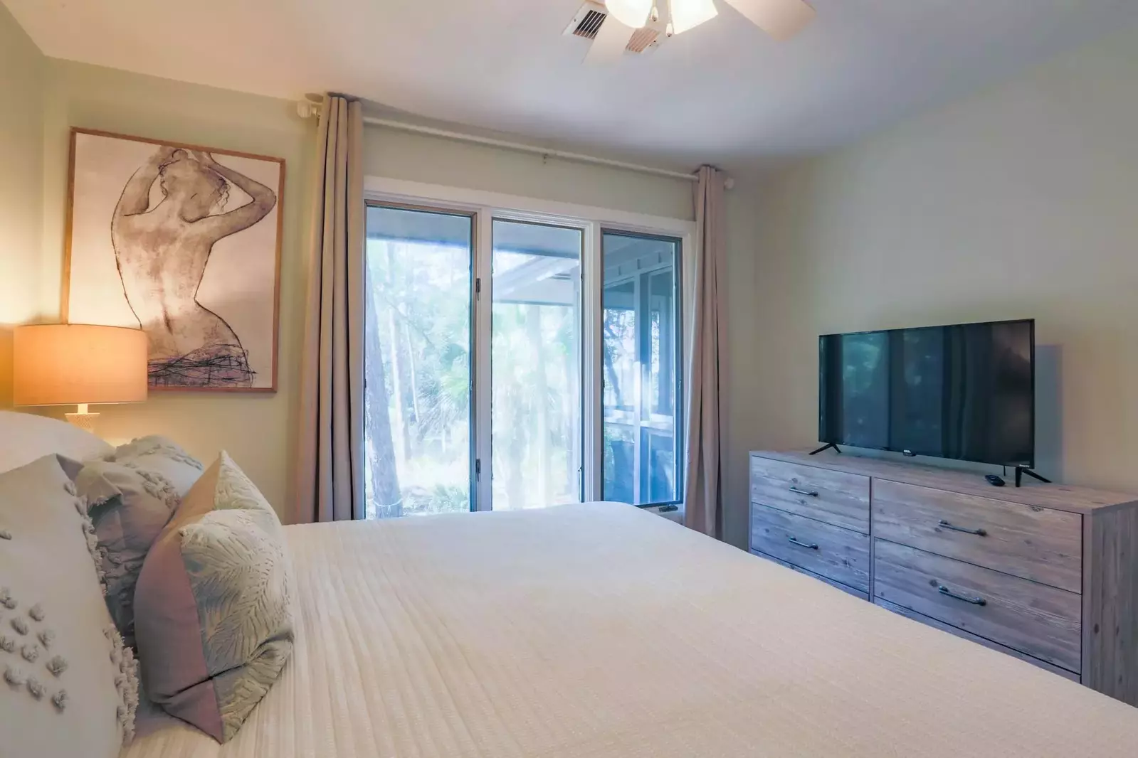 The guest bedroom also has a dresser, smart TV and a ceiling fan.