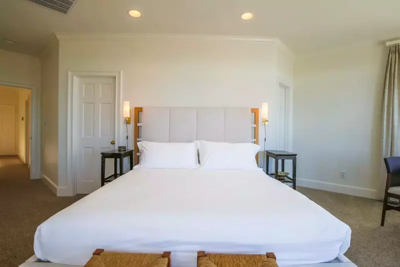 The master suite, located on the second floor, has a king bed with night stands and wall sconces.