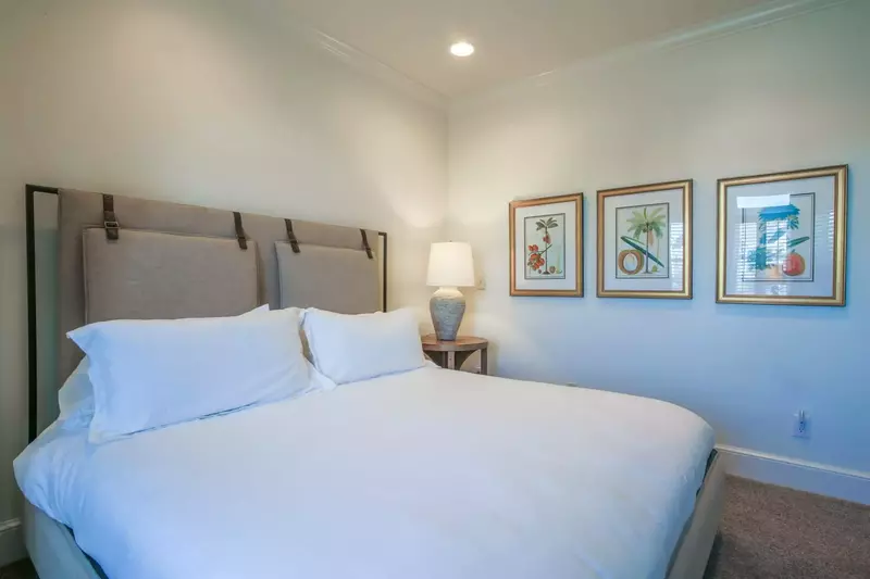 The second master suite features a king bed and a night stand with a reading lamp.