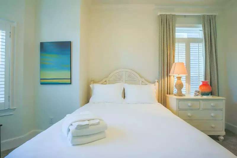 This guest bedroom features a queen bed and a night stand with a reading lamp.