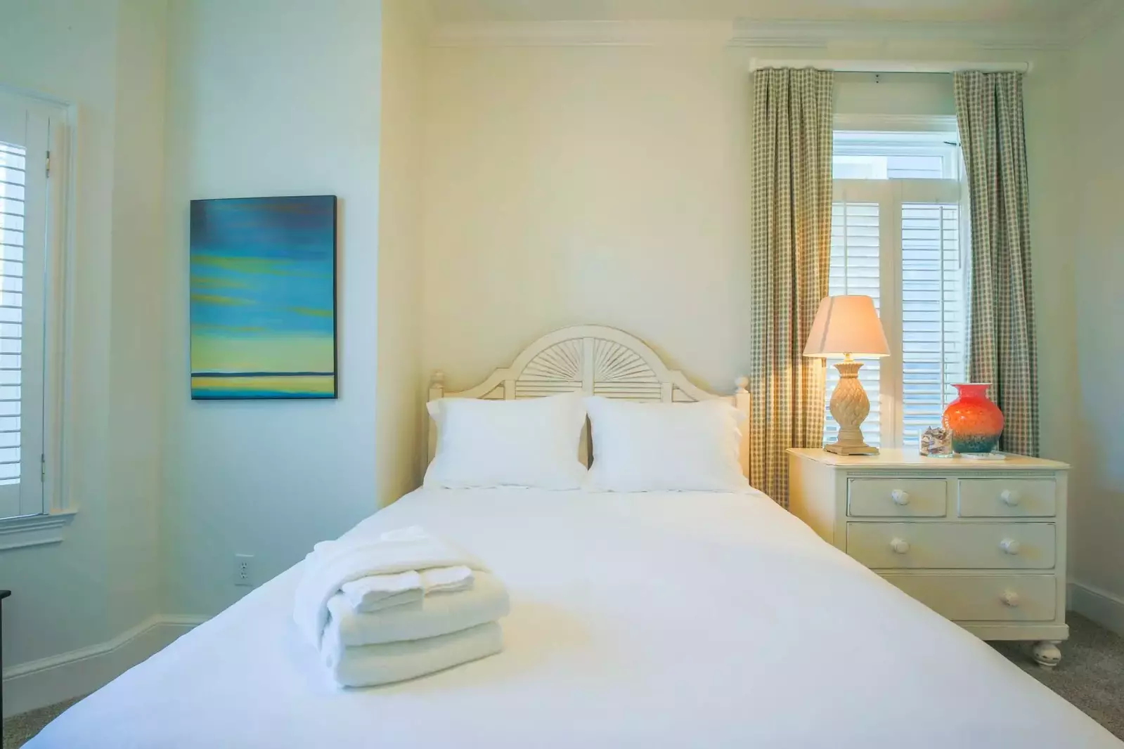 This guest bedroom features a queen bed and a night stand with a reading lamp.