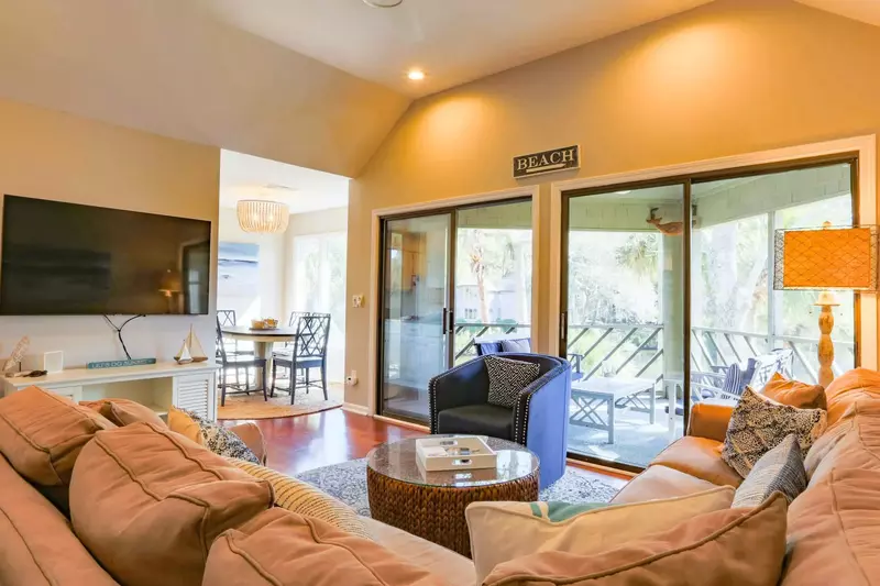 The living room features a large sectional, a mounted large screen TV and sliding door access to the porch.