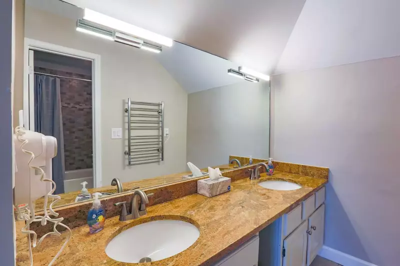The master bathroom features a double sink vanity and an electric towel warmer.