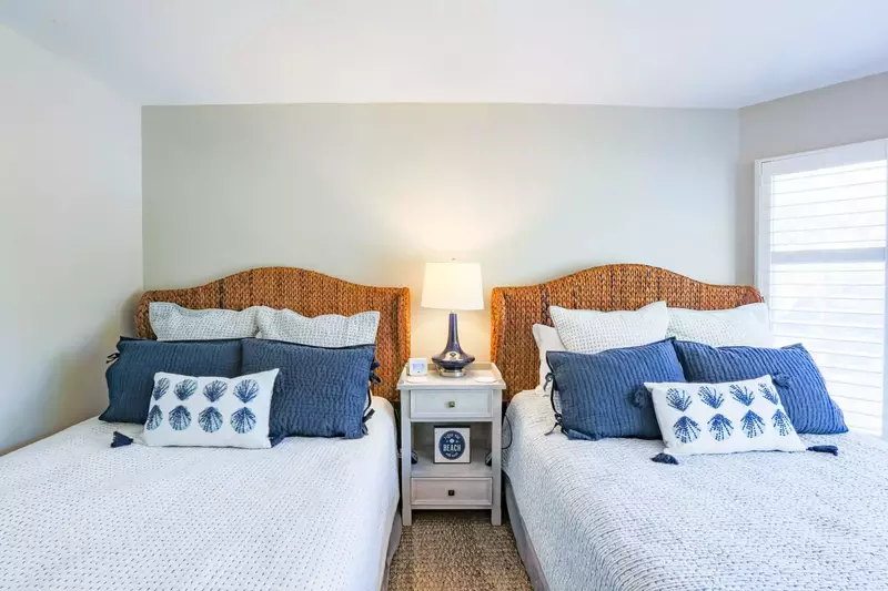 The guest bedroom features two queen beds, a night stand and a reading lamp.