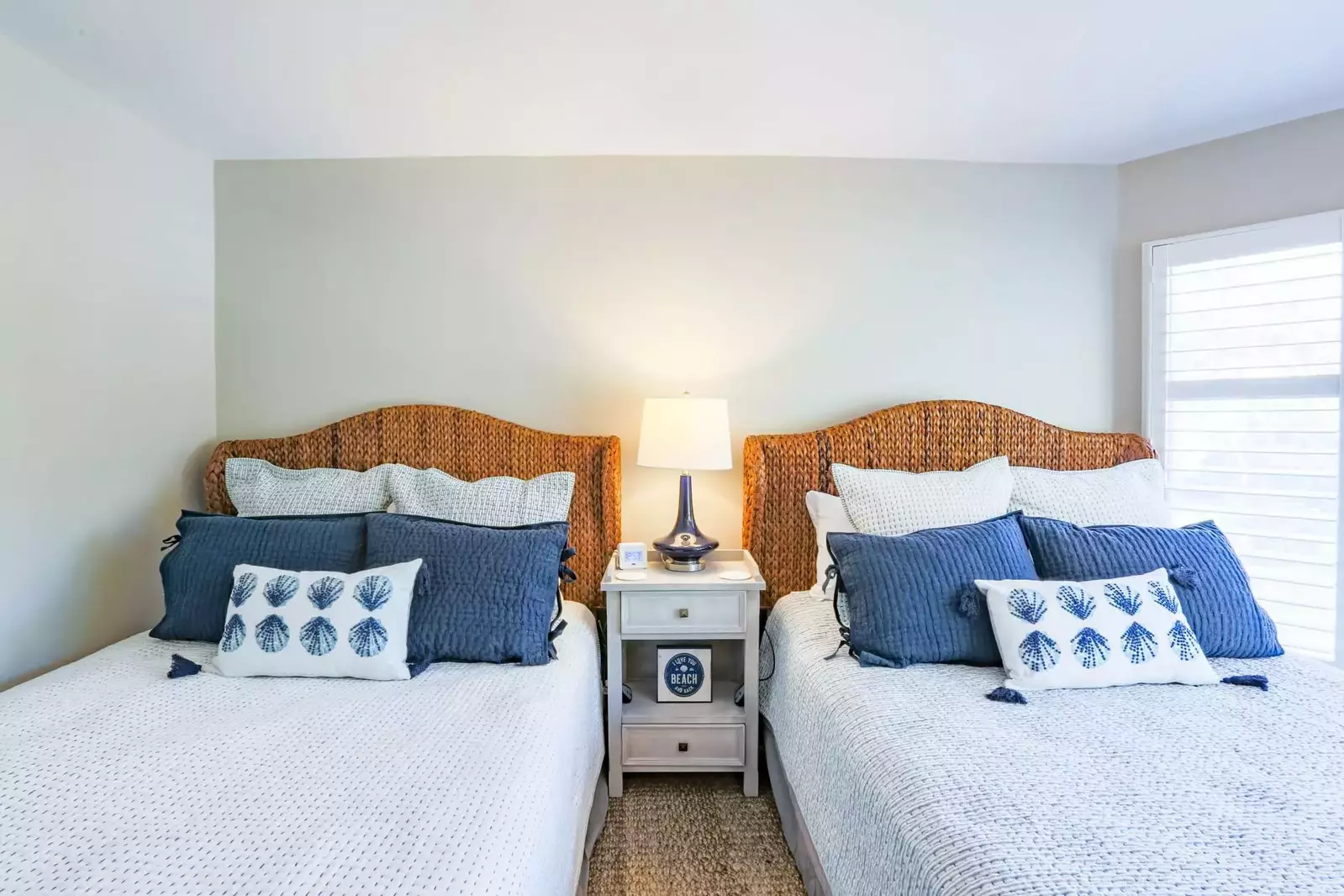 The guest bedroom features two queen beds, a night stand and a reading lamp.