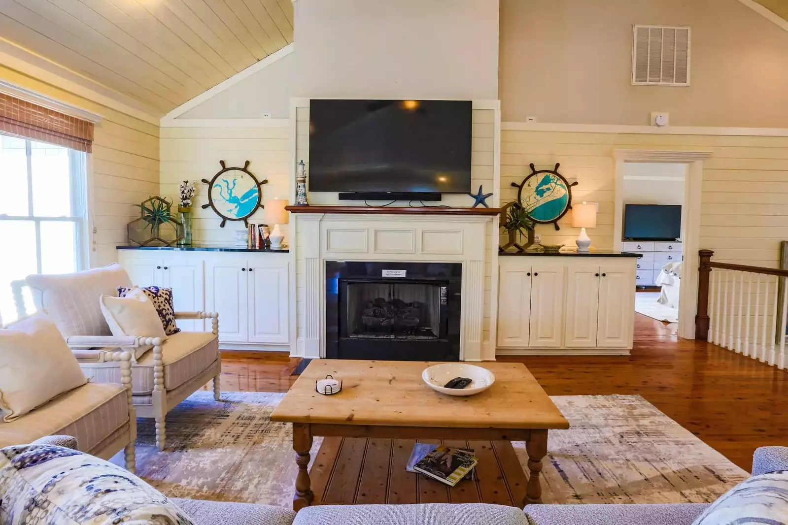The living room features a mounted large screen TV, comfortable seating and hardwood floors.