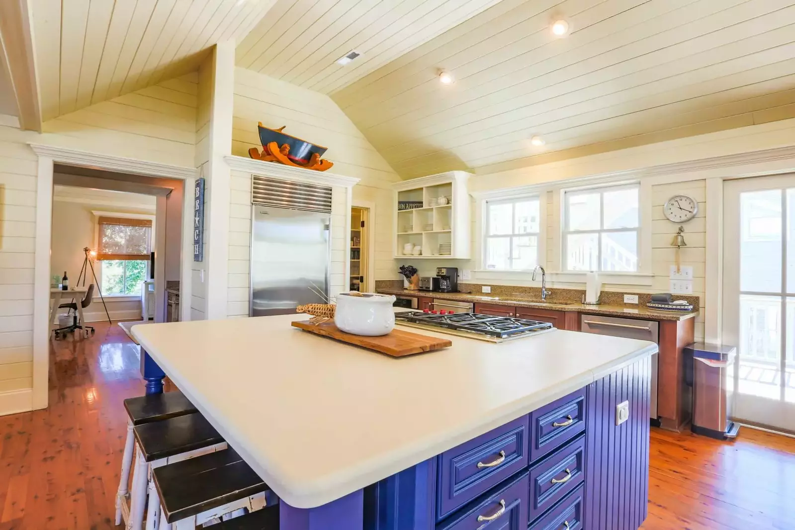 The kitchen features a central island with a gas cooktop, stainless steel appliances and a pantry.