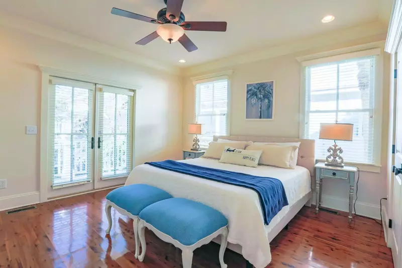 The second master suite features a king bed, night stands with reading lamps and a ceiling fan.