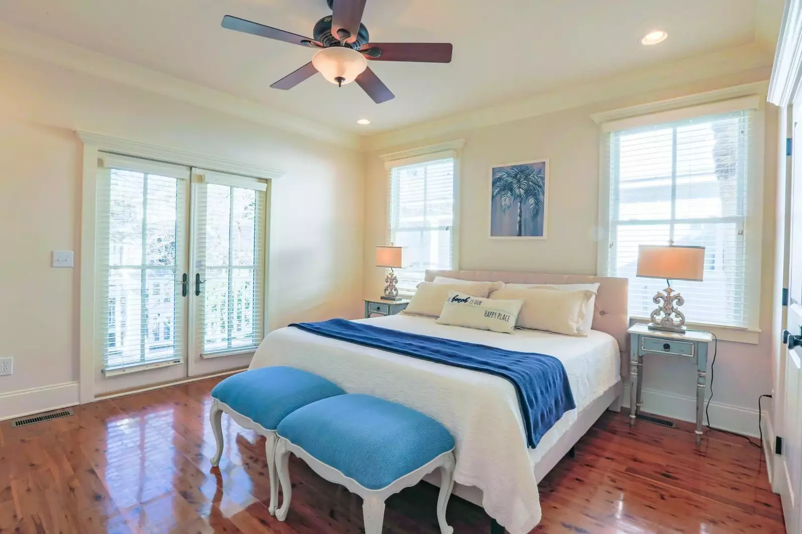 The second master suite features a king bed, night stands with reading lamps and a ceiling fan.