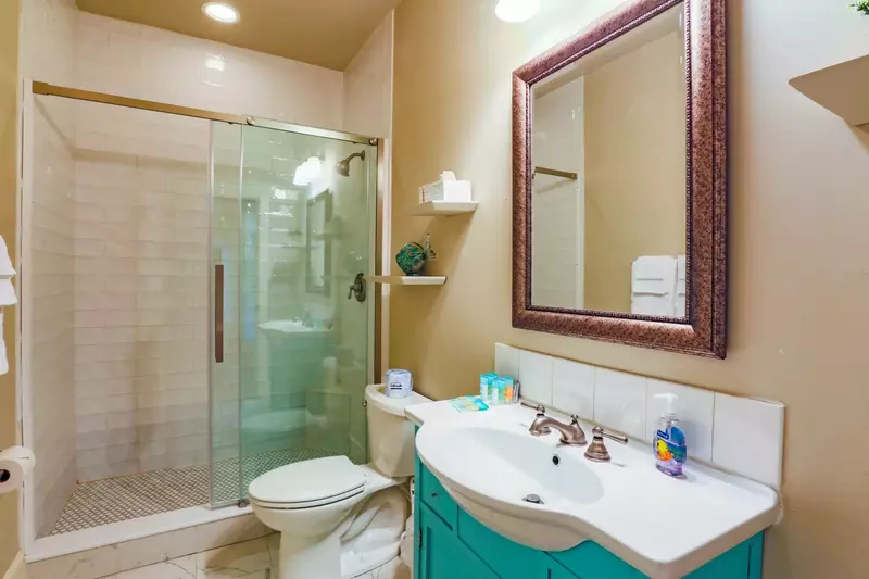This bathroom, which is accessible from the hallway, features a tiled, walk-in shower and spacious vanity.