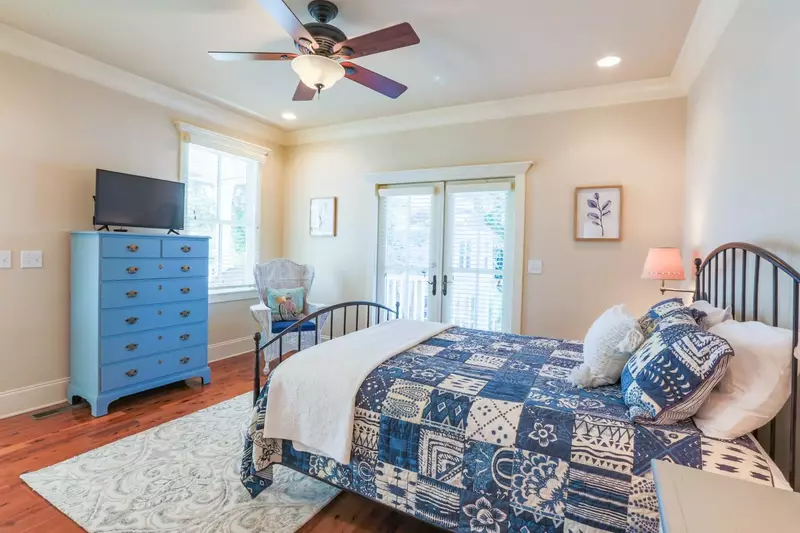 This guest bedroom features a queen bed and access to the back porch.