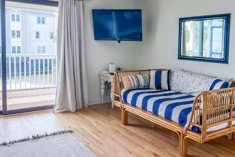 The master suite features has sliding door access to the covered porch, a mounted smart TV and a daybed.