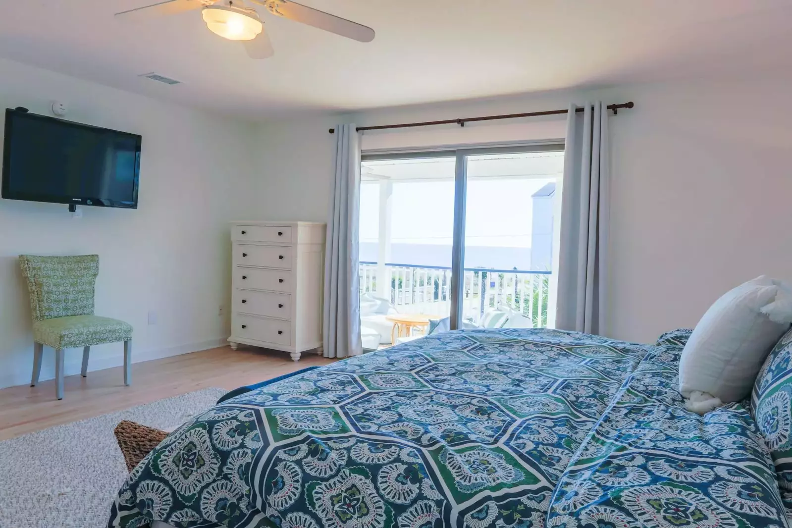 This guest bedroom also features stunning ocean views, sliding door access to the covered balcony and a smart TV.
