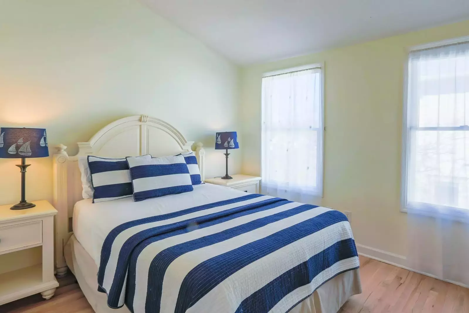 This guest bedroom features a queen bed and night stands with reading lamps.