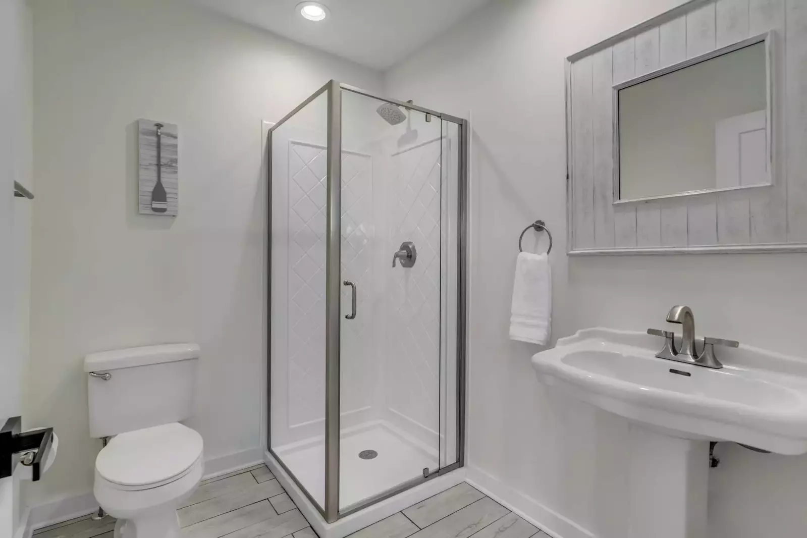 This bathroom near the kitchen features a walk-in shower and a pedestal sink.