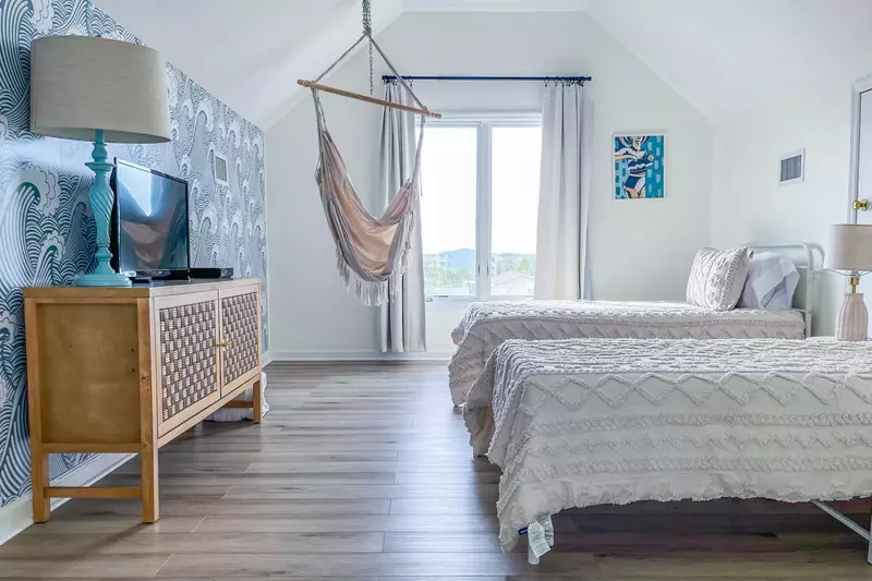 This loft bedroom features two twin beds, a chair swing and a smart TV.