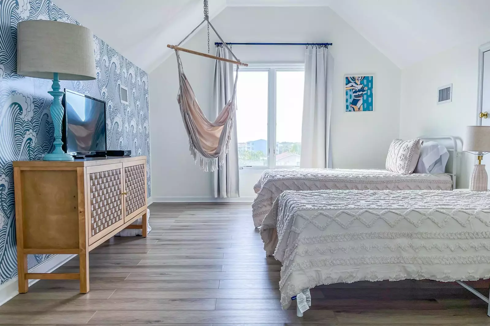 This loft bedroom features two twin beds, a chair swing and a smart TV.