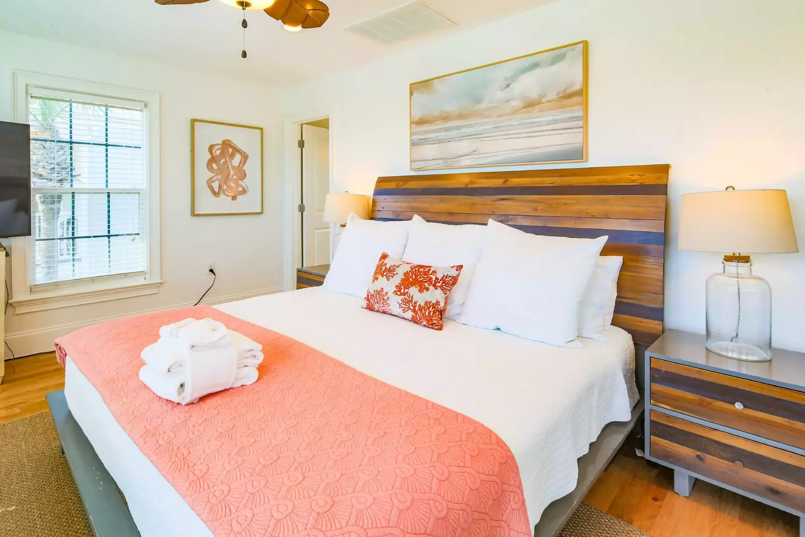 The master suite features a king bed, ceiling fan and night stands with lamps.