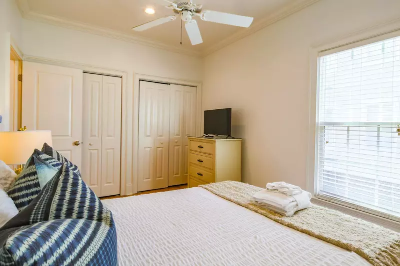 This guest bedroom also has a dresser, ceiling fan, two closets and a smart TV.