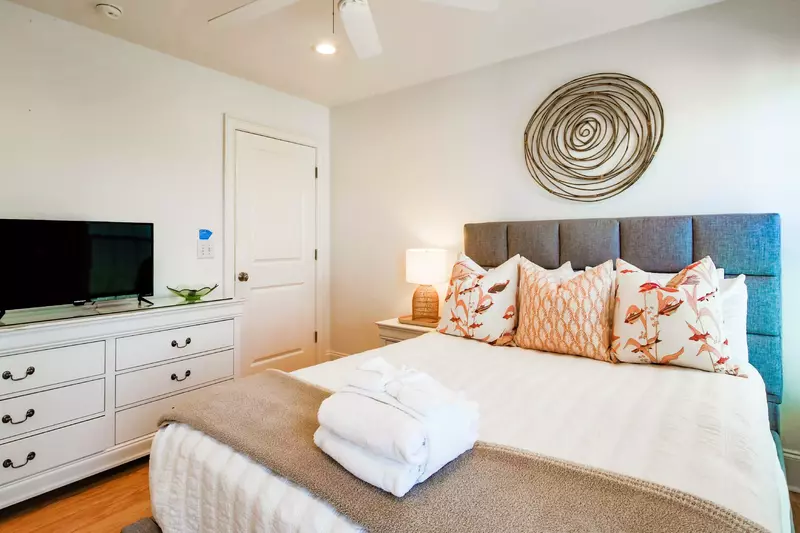 This second floor guest suite features a queen bed, a dresser and a smart TV.