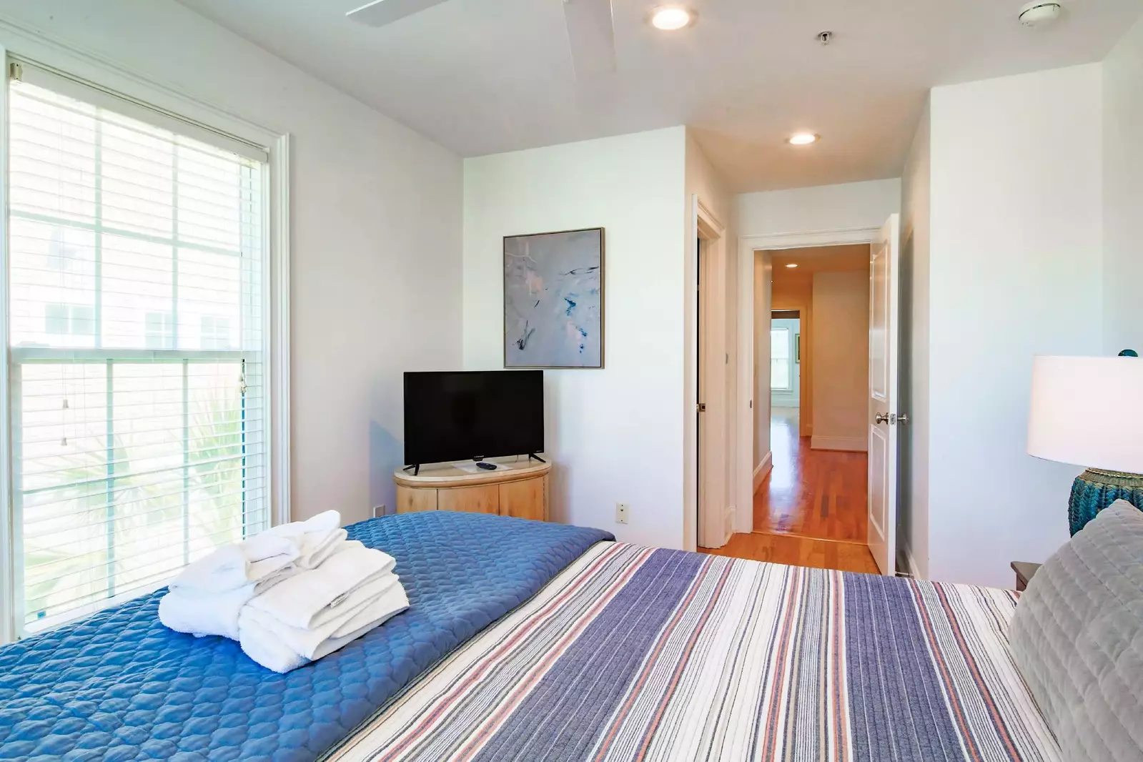 This guest bedroom also has a dresser, smart TV and ceiling fan.