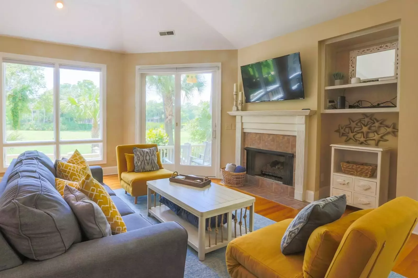 The living room features a mounted smart TV, vaulted ceilings and nearly floor-to-ceiling views of the fairway.