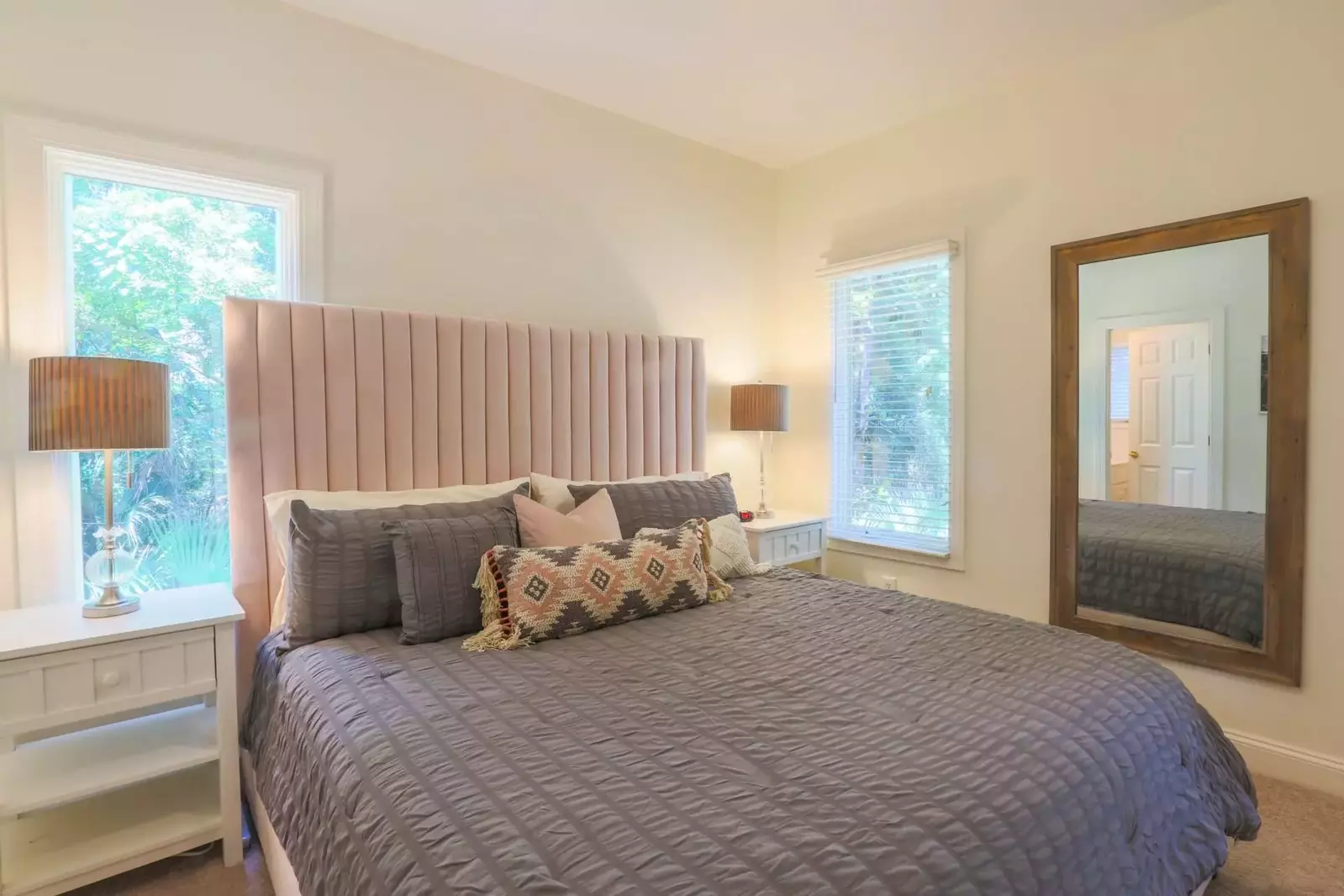 This bedroom on the lower level of the home features a king bed and night stands with reading lamps.