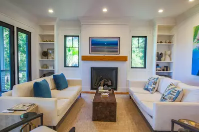 The living room features two sofas, armchairs and a mounted smart TV.