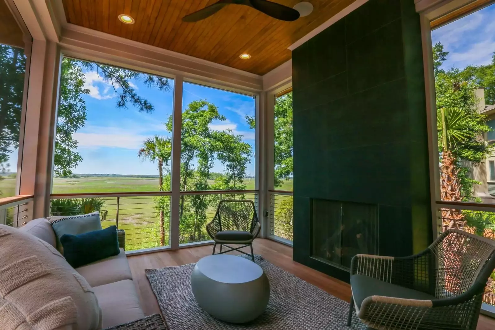 The screened porch situated off the living room features a cosy seating area and marsh views.