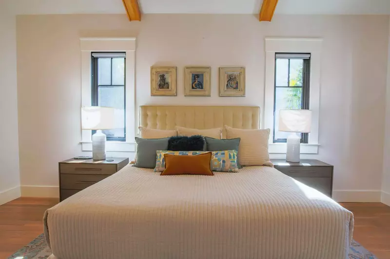 The primary bedroom features vaulted ceilings, a king bed and nightstands with reading lamps.