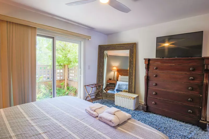 There is a dresser with a Smart TV, full length mirror and sliding door access to a private courtyard.
