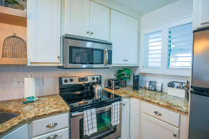 The kitchen features a new tiled backsplash, white cabinets and stainless steel appliances.