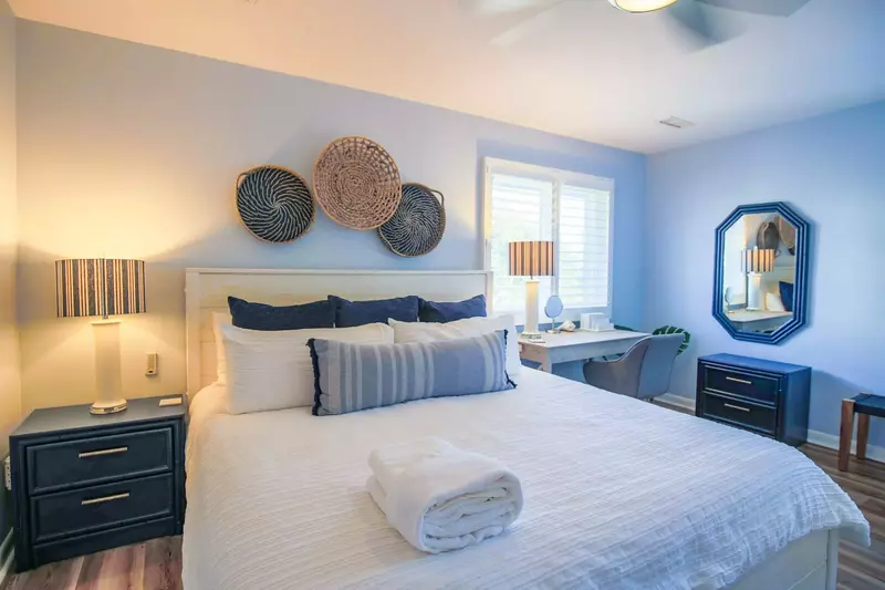 The bedroom features a king bed, night stand with reading lamp and workspace with desk chair.