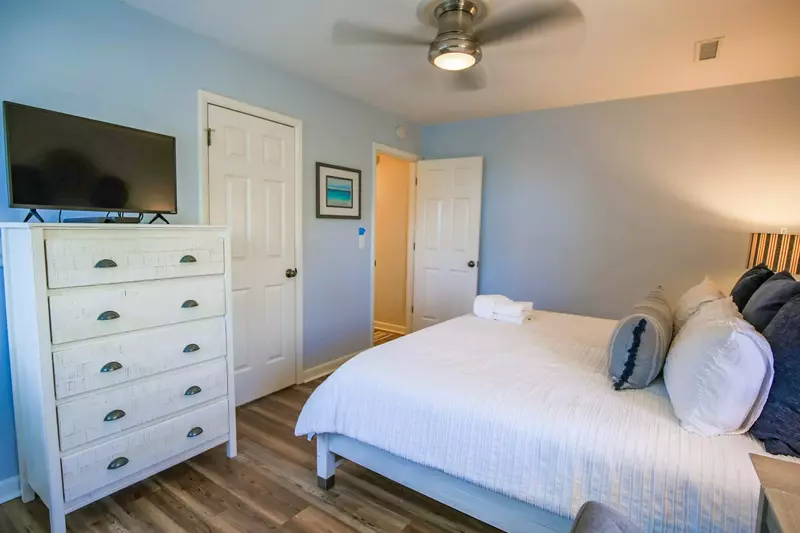 The bedroom also has a ceiling fan, dresser and TV.